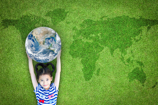 Earth day, ecological friendly and corporate social responsibility concept with kid raising world on green lawn: Element of the image furnished by NASA