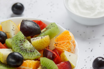 Fresh salad from kiwi, oranges, plums, grapes and chia seeds. Close up. Healthy lifestyle.