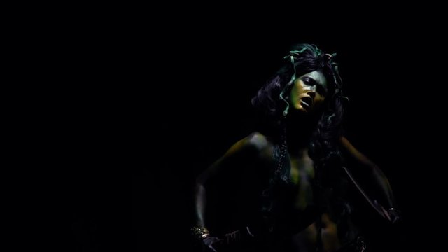 Medusa standing in the dark and swinging her blades