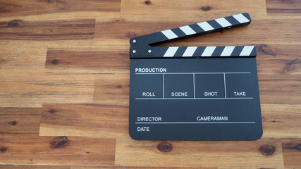 Black Clapperboard or clap board or movie slate use in video production, film ,cinema industry. It's black color on wood background .