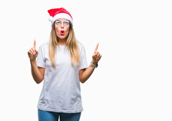 Young beautiful woman wearing christmas hat over isolated background amazed and surprised looking...