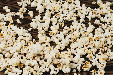 Fried popcorn scattered on old wooden table. Сoncept of leisure