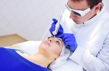the surgeon beautician removes pigmentation and vascular nets on the skin of the patient-a...