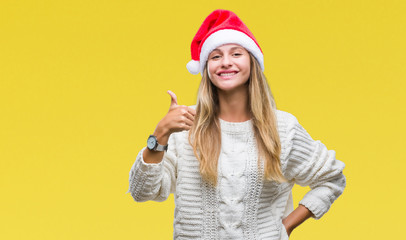 Fototapeta na wymiar Young beautiful blonde woman wearing christmas hat over isolated background doing happy thumbs up gesture with hand. Approving expression looking at the camera with showing success.