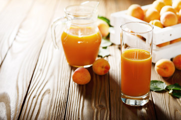 Apricot smoothie in glass on wooden table with crate and jug at background