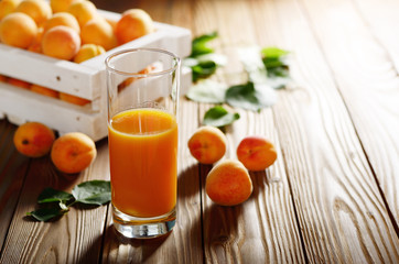 Apricot smoothie in glass on wooden table with crate at background