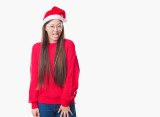 Young Chinese woman over isolated background wearing christmas hat sticking tongue out happy with funny expression. Emotion concept.