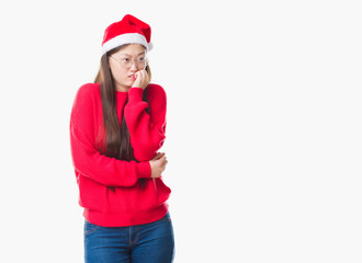 Young Chinese woman over isolated background wearing christmas hat looking stressed and nervous with hands on mouth biting nails. Anxiety problem.