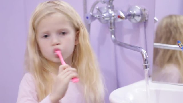 Happy blonde child kid girl laughing and brushing teeth with toothpaste. Health care, dental hygiene, people and beauty concept
