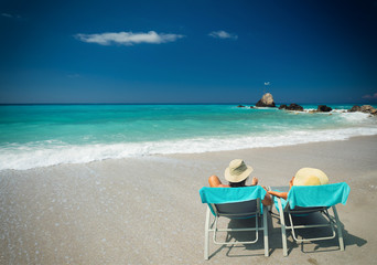 Couple on sunbeds relaxing at the beach in Lefkada