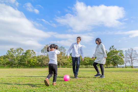 青空の公園でボール遊びをする夫婦。家族,妊娠,親子,愛、幸せイメージ