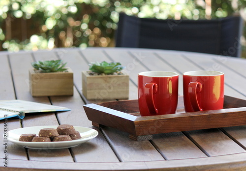 Outdoor table setting with red mugs and cookies