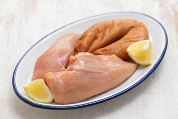 raw chicken breast with smoked sausage and lemon on dish