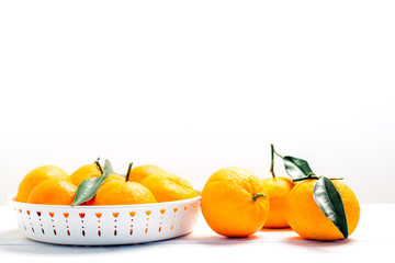 Pile of mandarins in white bowl on white wooden background