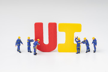 UI User Interface development and design concept, miniature people workers team building the colorful word UI with white background, user centric in modern world software, application and products