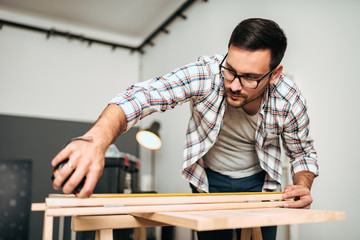 Young stylish craftsman holding measuring tape. Diy or home renovation concept.