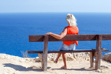  woman sitting on bench on seashore. Vacation and relaxation concept.