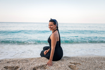 Portrait of a gorgeous smiling young woman sitting on the sand beach.