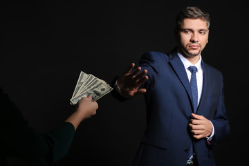 Businessman refusing to take bribe on dark background. Corruption concept