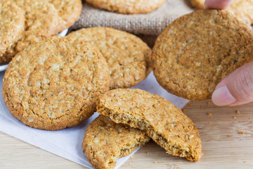 Woman hands holding homemade shortbread cookies made of oatmeal pile in plate on wooden table and sackcloth background. Concept food healthy snack for enjoy in holiday. with copy space for text.