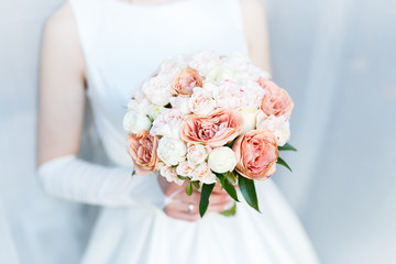 Sweet Wedding Bouquet with roses in the Hands of the Bride