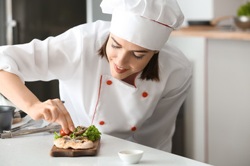 Young female chef preparing tasty dish in kitchen