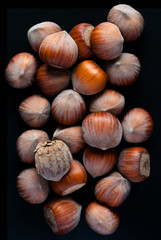 Hazelnuts . Whole nuts, shelled. Ground hazelnuts and hazelnut brittle. Macro photo, close up, top view, isolated, on black background.