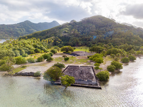 Ancient Marae Taputapuatea temple complex on the lagoon shore with mountains on background. Raiatea island. French Polynesia, Oceania.