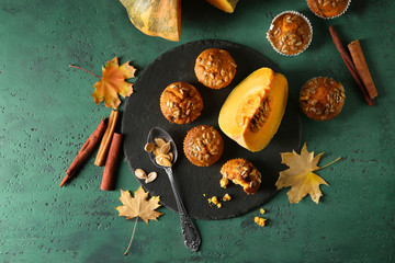 Composition with tasty muffins, cut pumpkin and cinnamon on color table