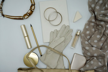 Flat lay composition of beauty products and handbag for women. Pastel and gold colors on white background. Top view.       