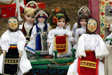 Different types of porcelain and wooden dolls dressed in folklore costumes put up for sale at a...