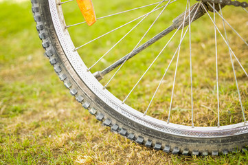 Tyre of a cycle with spokes parked on green grass. Selective focus.