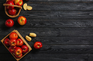 Naklejka na ściany i meble Box and wicker basket with ripe tasty apples on dark wooden background