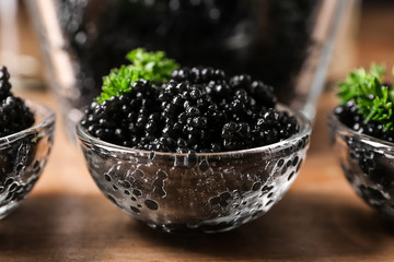 Fototapeta na wymiar Bowls with delicious black caviar on wooden table