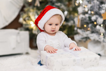 Baby girl or boy in a red hat of Santa Claus in a Christmas decorations