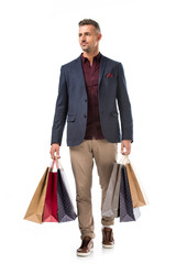 adult stylish man in jacket holding colorful shopping bags isolated on white