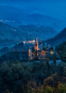 Veduta notturna di paese collinare con chiesa e campanile illuminati sui Colli Euganei