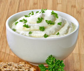 Fresh greek yogurt or cream cheese with herbs on wooden table