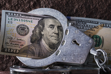 100 dollars in handcuffs close-up. Concept on the limitation of dollar circulation in different...