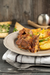 Roast pork with herbs and vegetables on rustic wooden table.