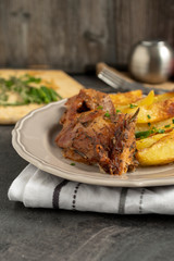 Roast pork with herbs and vegetables on rustic wooden table.