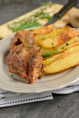 Roast pork with herbs and vegetables on rustic wooden table.