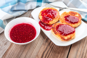 Cottage cheese pancakes, cheesecakes  with raspeberry  jam on wooden background, healthy traditional  breakfast