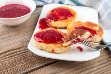 Foto op Plexiglas Cottage cheese pancakes, cheesecakes  with raspeberry  jam on wooden background, healthy traditional  breakfast © sola_sola