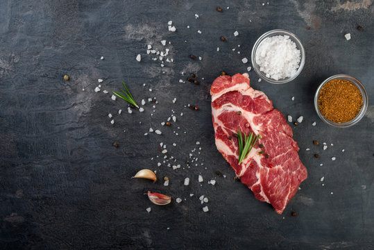 Raw beef steak with spices on black background. Flat lay.Top view