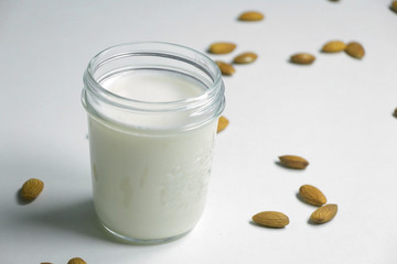Almond milk with almond on a white table. Plant based milk