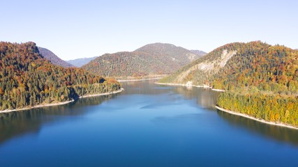 Autumn color forest, aerial view over colorful autumn trees, towards lake and on a sunny fall day