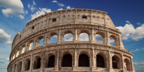 Fototapeta premium Detail of the arches of the Colosseum. Marble ruins over a blue sky, Rome, Italy