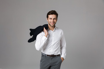 Image of caucasian businessman 30s smiling and holding jacket over his shoulder, isolated over gray background