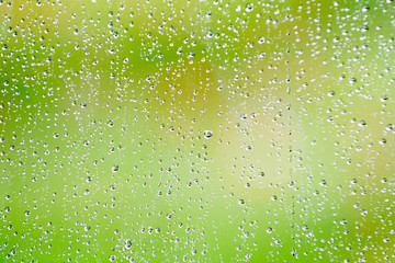 Rain drops on glass window with fresh outdoor background